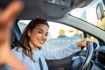 Smiling young woman taking selfie picture with camera in car. Holidays and tourism concept -...