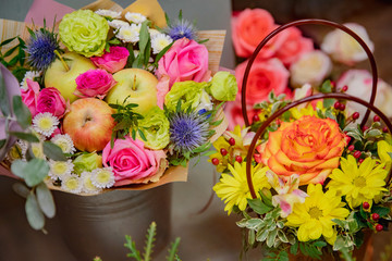 Florist makes autumn bouquet of roses flowers, apples red, green and yellow leaves
