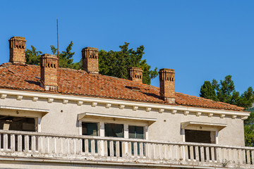 Stone building with a balcony, chimneys and tiled roof.