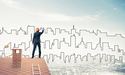 Man architect draw silhouette of modern city on blue sky. Mixed