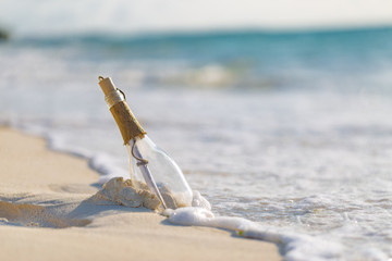 Message in a bottle washed ashore on a tropical beach. Castaway concept, tropical beach dreamy background