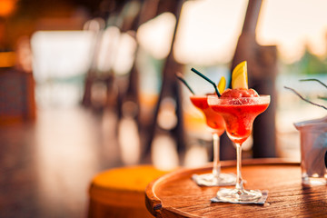Red cocktails on blurred bar background. Couple drinks
