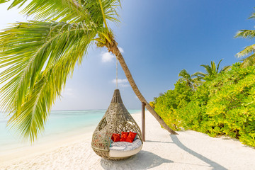 Beautiful tropical Maldives beach under cloudy sky with swings or hammock on coconut palm. Luxury vacation concept