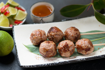 Close-up of nem nuong or fried vietnamese pork meatballs on skewers, selective focus