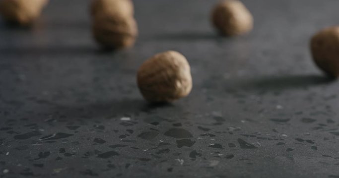 Slow motion shelled walnuts rolls in frame on terrazzo countertop