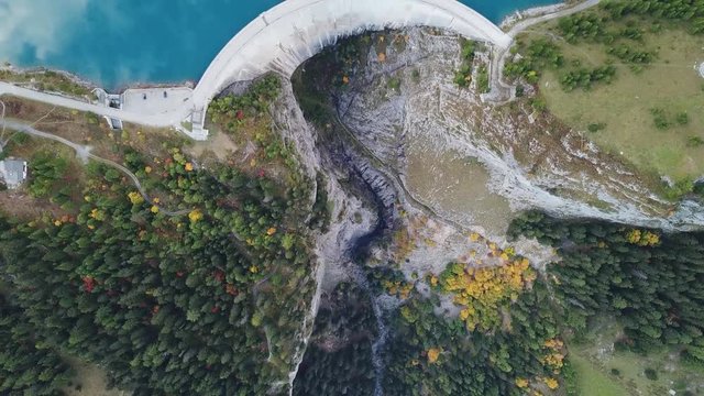 Hydroelectricity generated from water dam and reservoir lake in Swiss Alps mountains to produce renewable energy and limit global warming, sustainable hydropower, aerial drone footage 4K 60fps video