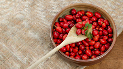 rote frische Hagebutten in einer Schale auf Jutesack 