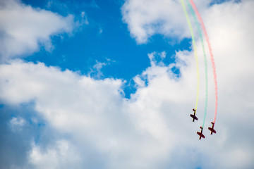 Aerobatics, air show. Aircraft team performing in the sky with old airplanes and drawing drawing Lithuanian flag, white clouds and blue sky