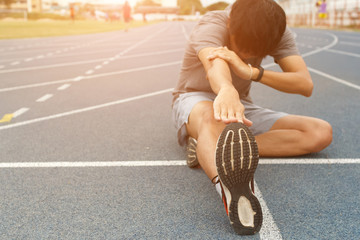 Young man runner stretching legs before run - workout concept