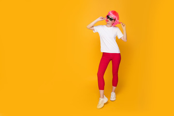 Fototapeta na wymiar Woman model in the yellow studio with lollipop in a pink wig and bright clothes