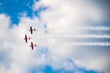 Aerobatics, air show. Aircraft team performing in the sky with old airplanes and drawing lines, white clouds and blue sky