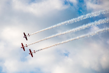 Aerobatics, air show. Aircraft team performing in the sky with old airplanes and drawing lines, white clouds and blue sky
