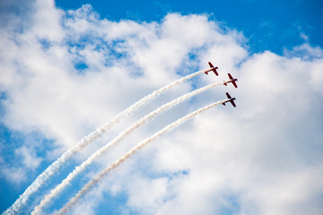 Aerobatics, air show. Aircraft team performing in the sky with old airplanes and drawing lines, white clouds and blue sky