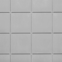 A wall of gray large square tiles with metal fasteners