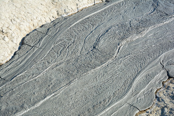 Fototapeta na wymiar Mud flow from a mud volcano. Cracked mud surface. Mudflow texture with cracks.