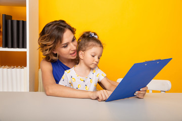 Mother and daughter reading sitting at home at the table