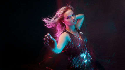 Fototapeta na wymiar Attractive dancing blonde in the club, neon light, motion effects