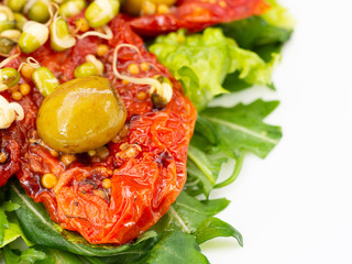 The salad consists of sun dried tomatoes greens various plants spices sprouted mung beans.