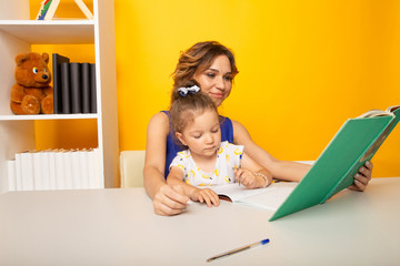 Mother with daughter studying together sitting at the table at home isolated