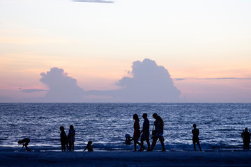 People walking at the beach with Clouds hiding the sun