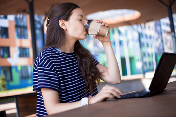 Close-up, portrait of a serious, gently smiling girl student, freelancer, blogger working at a...