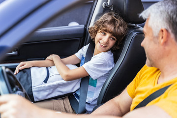 Little boy looking at his mature father in the car