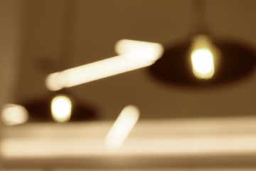 Blurred view of modern lamp on the ceiling. Beige toning. Monochrome image. Can be used as backdrop