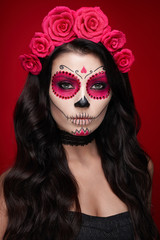 Portrait of a woman with sugar skull makeup over red background. Halloween costume and make-up. Portrait of Calavera Catrina