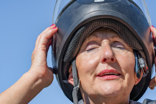 Older Woman Putting On Motorcycle Helmet, Expression Of Happiness