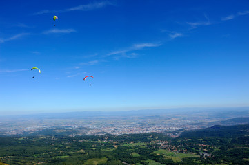 Fototapeta na wymiar Paragliders in full flight over volcanoes of Puy de Dome