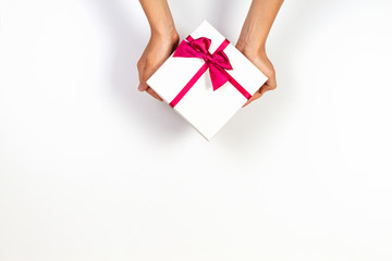 Child hands holding present gift box tied with ribbon on white background. Top view, place for text. Holiday concept