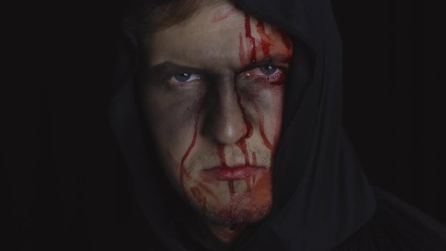 Man executioner Halloween makeup and costume. Guy with blood on his face