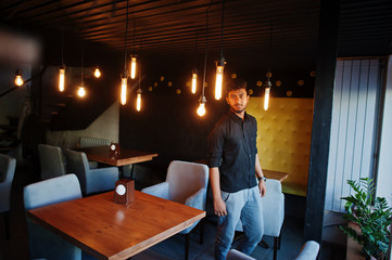 Confident young indian man in black shirt standing at cafe.