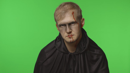 Fototapeta premium Man executioner Halloween makeup and costume. Guy with blood on his face