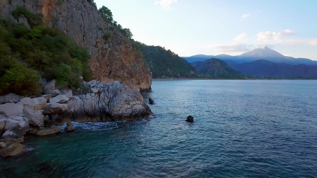 Aerial along the coast near Olympos Beach in Turkey. High drone forward dolly over the ocean