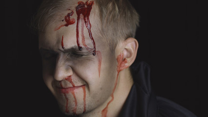 Halloween man portrait. Guy with dripping blood on his face. Scary makeup