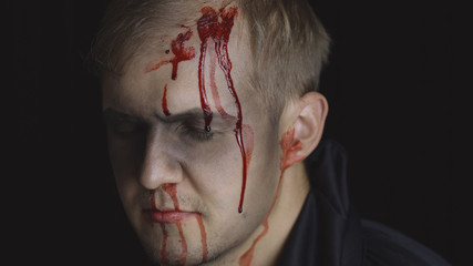 Halloween man portrait. Guy with dripping blood on his face. Scary makeup