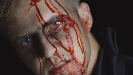 Halloween man portrait. Guy with dripping blood on his face. Scary makeup