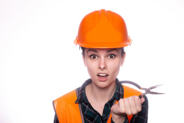 beautiful young girl worker in a helmet holds pliers in her hand