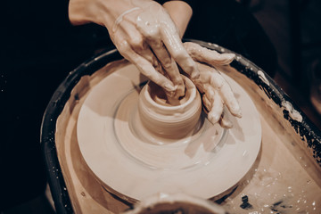 master makes a vase of clay, clay circle, close-up hands, mug of raw clay, hands made