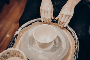 master makes a vase of clay, clay circle, close-up hands, mug of raw clay, hands made