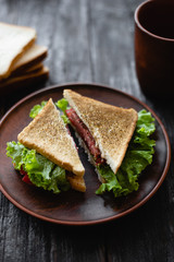 a delicious breakfast on the table, a sandwich with ham and lettuce is cut in two.