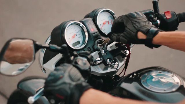 Motorcycle ignition action. Motorcyclist inserting the key and starting the engine