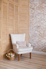 soft armchair near brick and wooden wall. Arm-chair with fabric upholstery