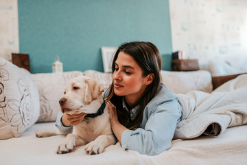 Close-up image of beautiful brunette woman cuddling with her puppy.