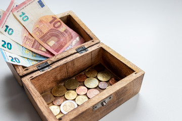 Euro-Scheinen und Euro-Münzen in einer offenen Schatztruhe aus Holz zeigen Reichtum, Finanzmanagement, Prämien, passives Einkommen, Sparsamkeit und finanzielle Sicherheit