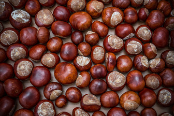 Heap of fresh chestnuts close up on rustic wooden background. Top view point.