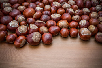 Ripe chestnuts on old wooden table  close up with copy space. Raw Chestnuts for Christmas.