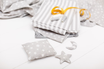 process of sewing of bed linen and little cute decorative pillow, star and moon. Sewing kit. Grey fabric, threads, measuring tape and sewed objects on white wooden background