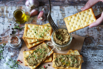 Male hands put the home liver pate on a cracker with a fork. Delicious homemade pate with spices...